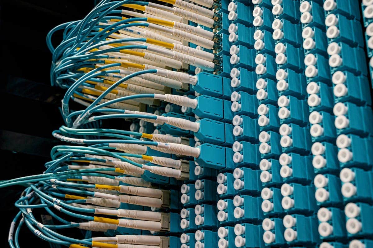 Patch panel con cables de fibra óptica de distintos colores en un datacenter profesional, donde el cable amarillo identifica la fibra monomodo G.652 y el aqua la multimodo OM4, facilitando la selección del módulo SFP correcto para cada puerto